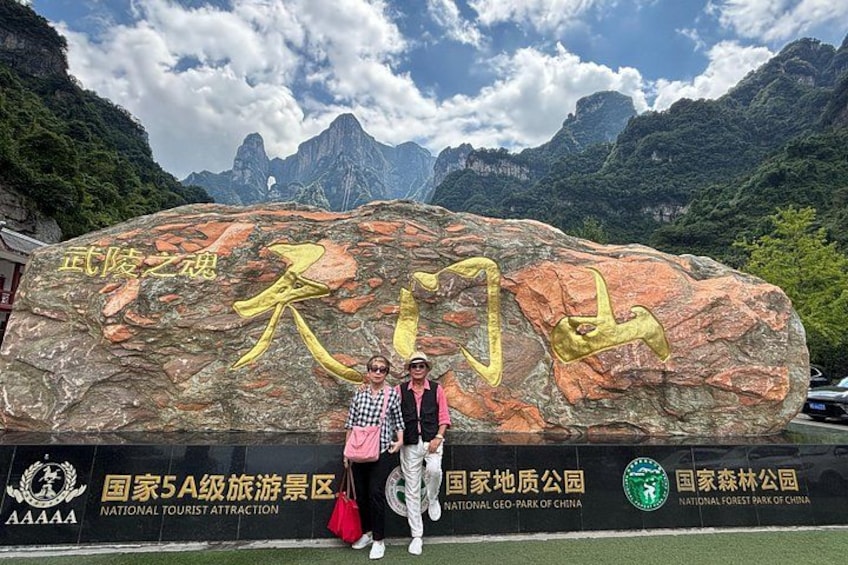 A large rock with Chinese characters, a tourist attraction sign, and logos for the National Tourist Attraction, National Geo-Park of China, and National Forest Park of China. 1