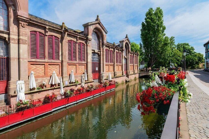 A canal with a building featuring red shutters and a bridge. 3