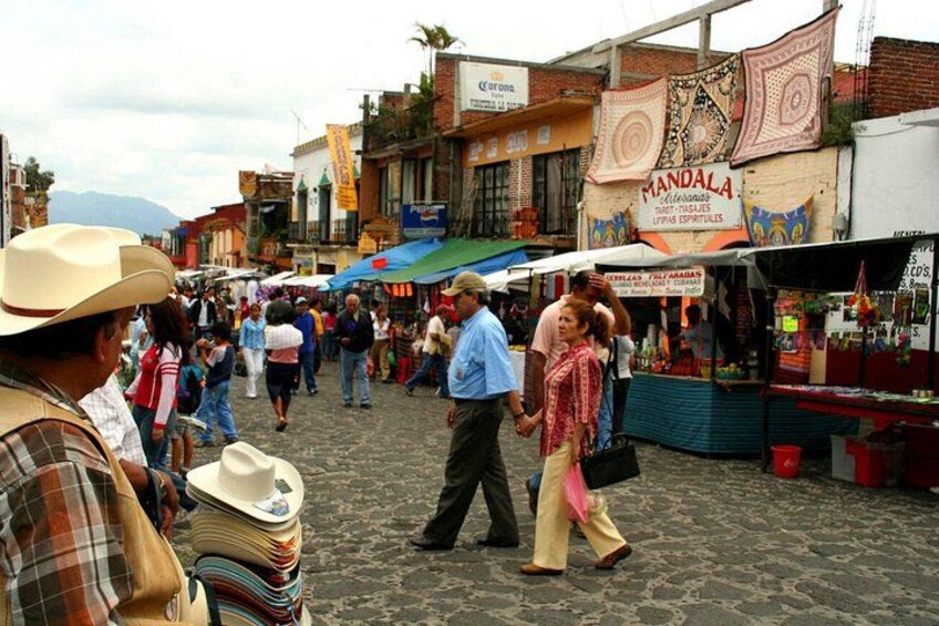 A bustling street market with people walking and vendors selling goods. 4