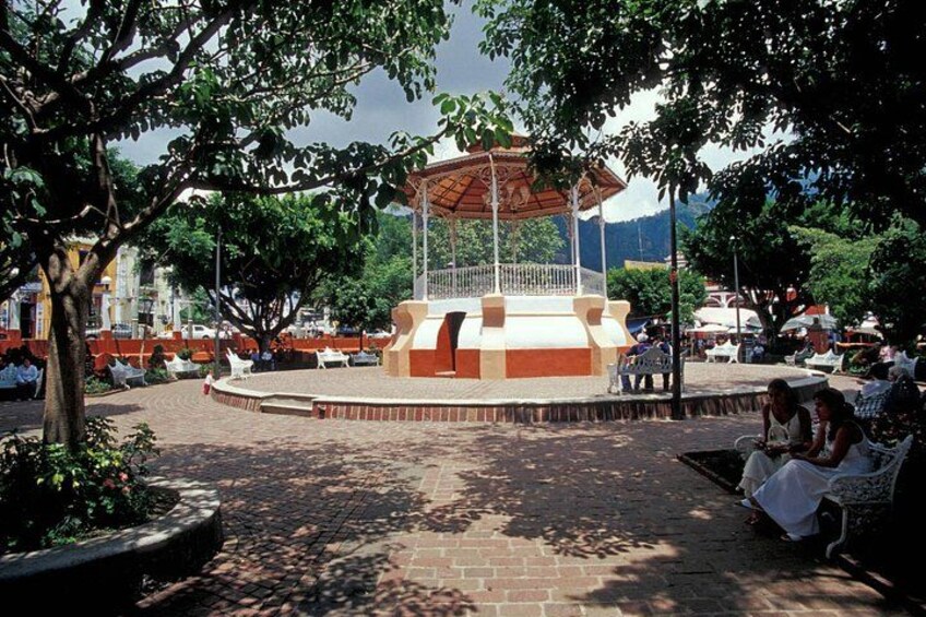 A park with a central gazebo, paved pathways, and benches. 3