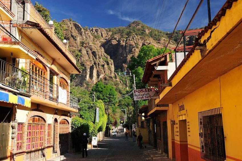 A street with buildings, a mountain, and a sign for a restaurant. 5