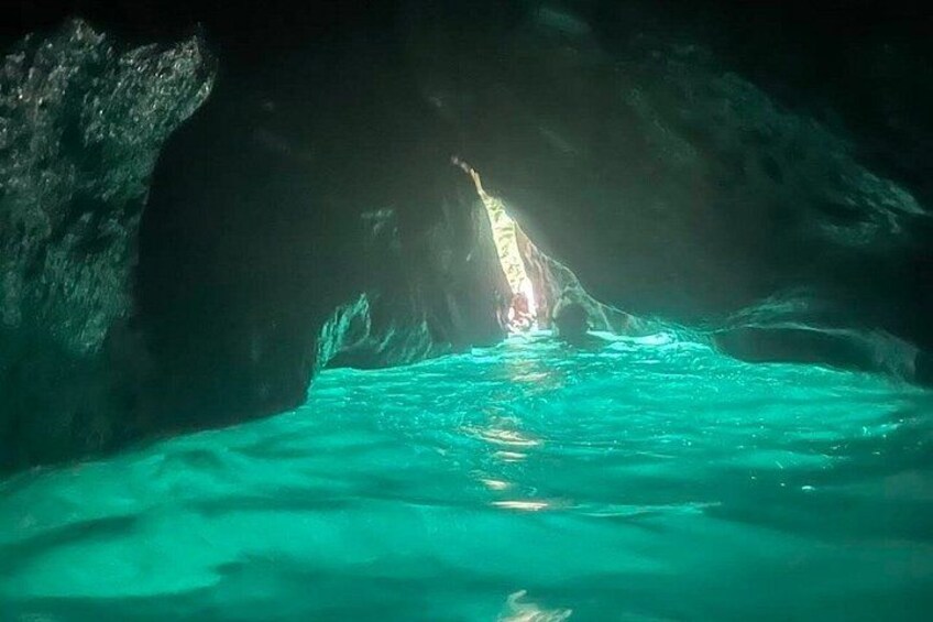 Une grotte avec de l’eau turquoise et une source de lumière au fond. 3