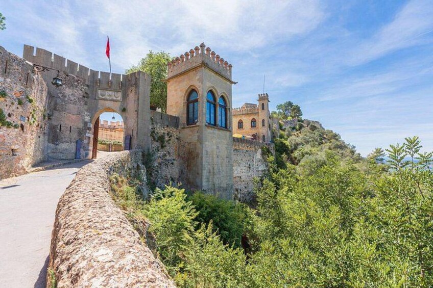 A historic stone wall with a small tower, a flag, and a gate. 4