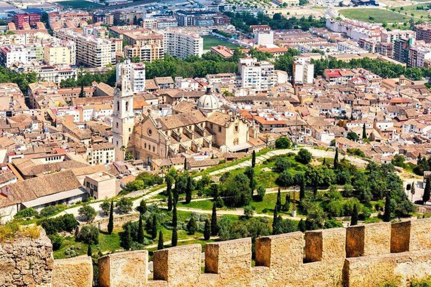 A historic cityscape with medieval architecture, a prominent church, and a fortified wall. 2