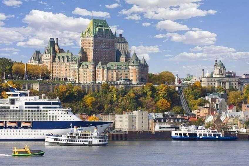 A cruise ship docked near a historic castle and a cityscape with autumn foliage. 1