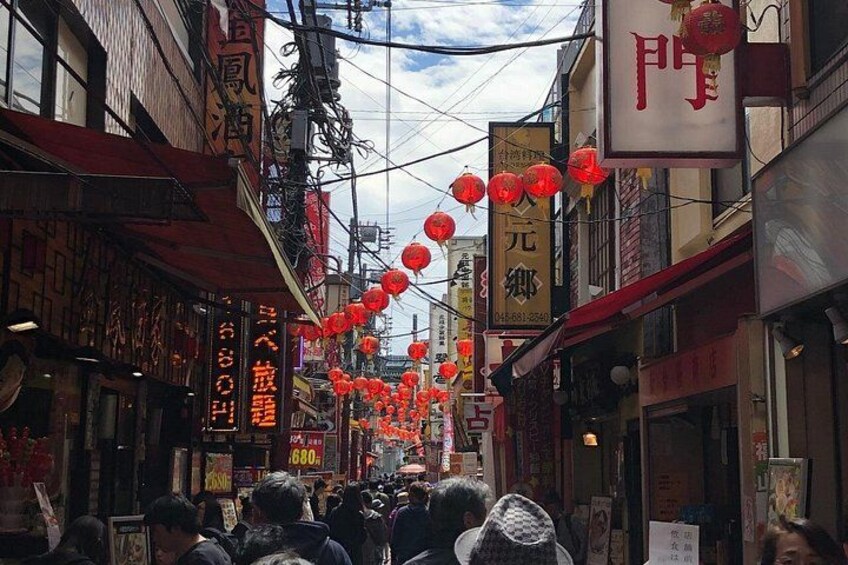 A street lined with traditional buildings, red lanterns, and signs with Chinese characters. 2
