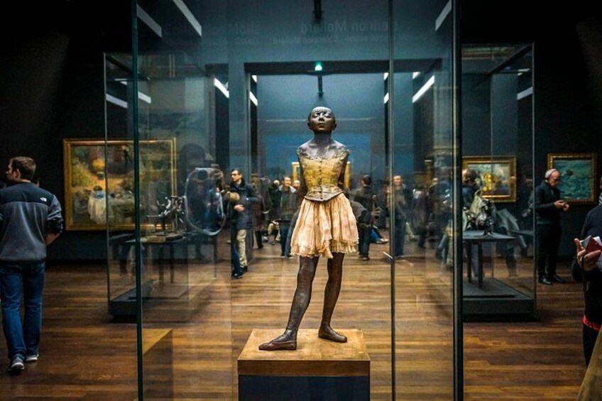 Et museumsinteriør med en mannequin i kjole, glasskabineudstillinger og besøgende. 4