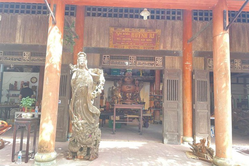 A traditional building with a statue of a deity, wooden pillars, and a signboard. 4