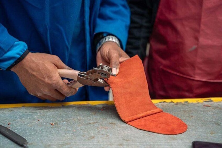 En person bruger et værktøj til at skære et stykke orange materiale på en arbejdsbord. 2