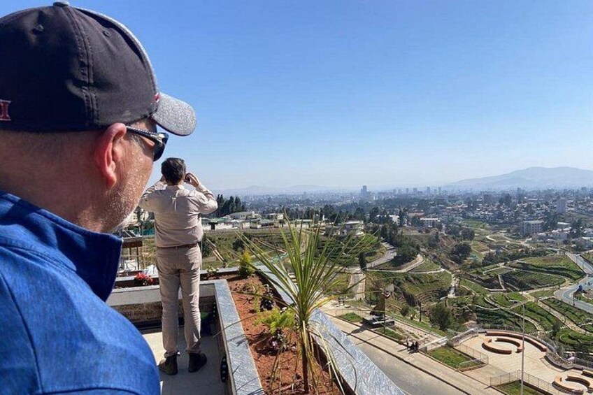 Un hombre con camisa y gorra azul, una mujer con uniforme color beige, y un paisaje urbano con montañas al fondo. 3