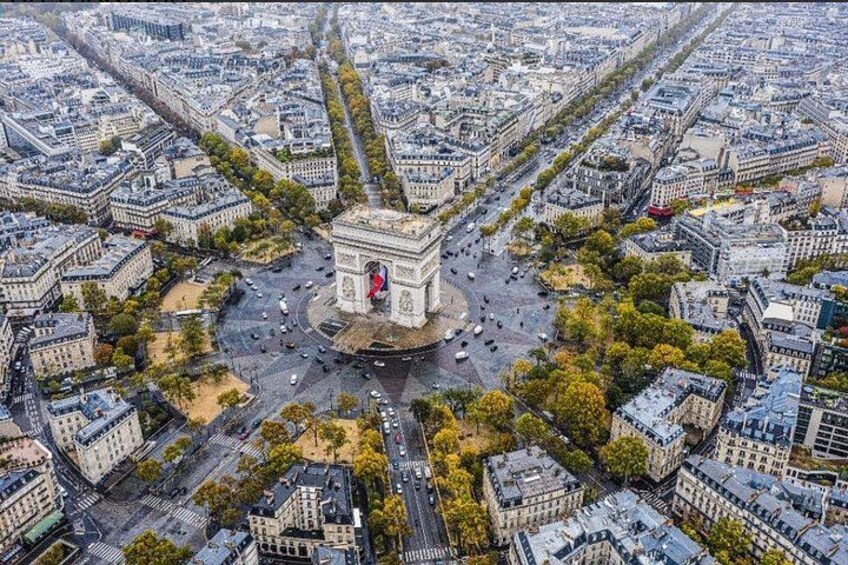 Une vue aérienne d’une ville, avec un monument imposant au centre, entouré de bâtiments urbains denses et de rues qui se croisent. 2