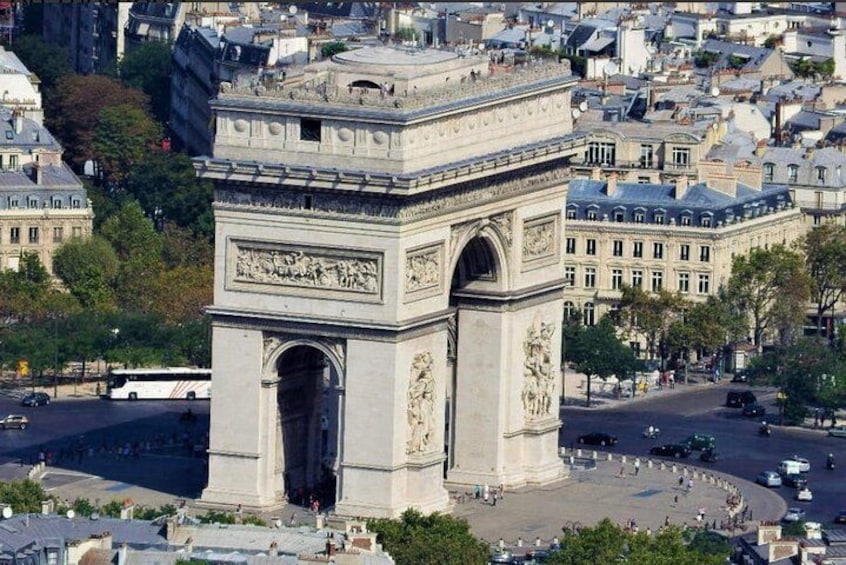 The Arc de Triomphe in Paris, surrounded by city buildings and a busy street. 1