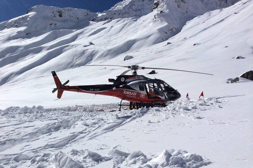 A red and black helicopter on a snowy mountain with flags. 1