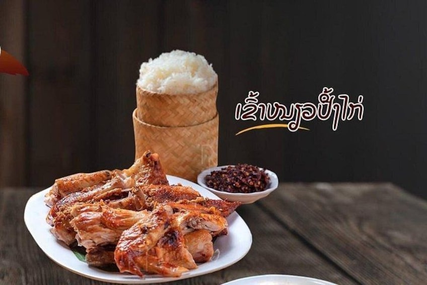 Roasted chicken, rice, and chili peppers on a wooden table. 1