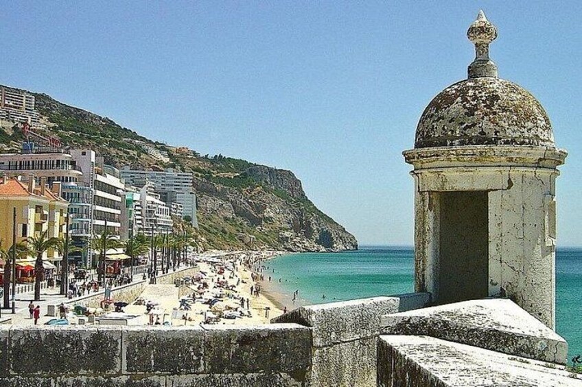 Eine Küstenstadt mit Strand, Gebäuden und einem historischen Turm. 5