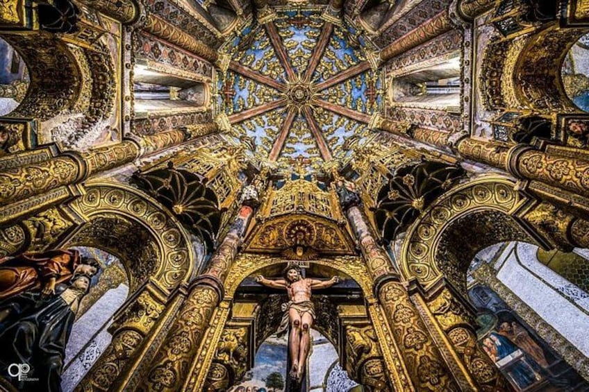 An ornate ceiling with intricate golden designs and a central figure. 4