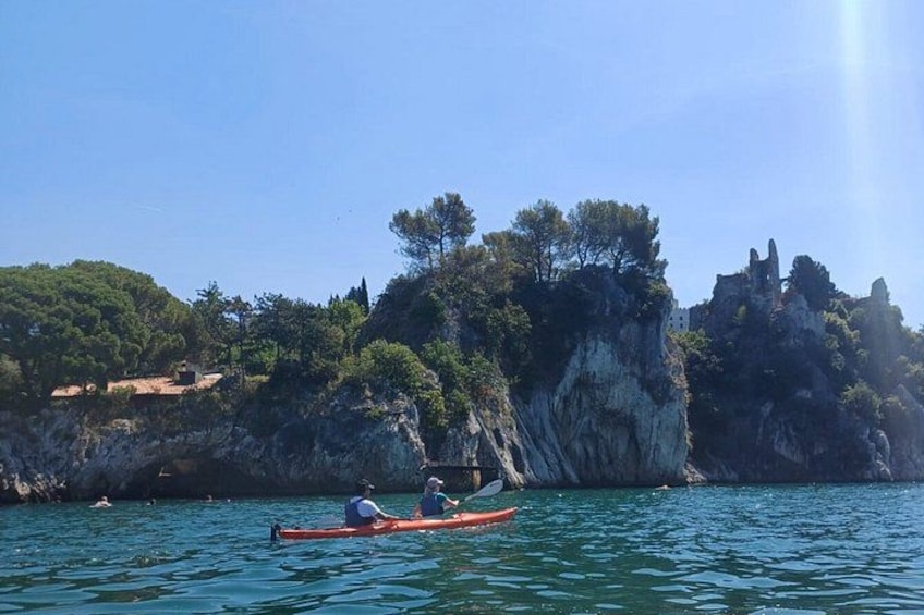 A kayak on calm water, rocky cliffs, and sparse vegetation. 5