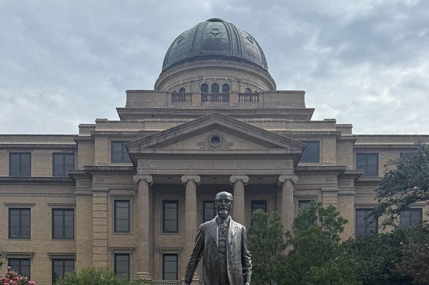 A large building with a dome and columns, a statue in front, and trees around. 3