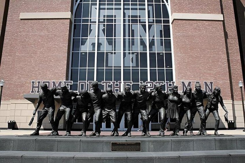 A bronze statue of athletes in front of a building with the inscription 'HOME OF THE BRAVES.' 1