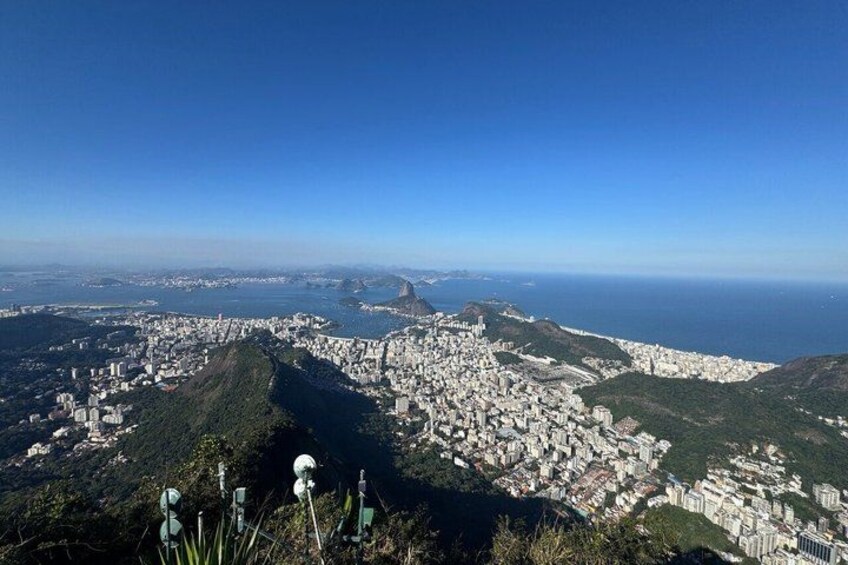 A panoramic view of a coastal city with a prominent hill, dense urban area, and a clear sky. 3