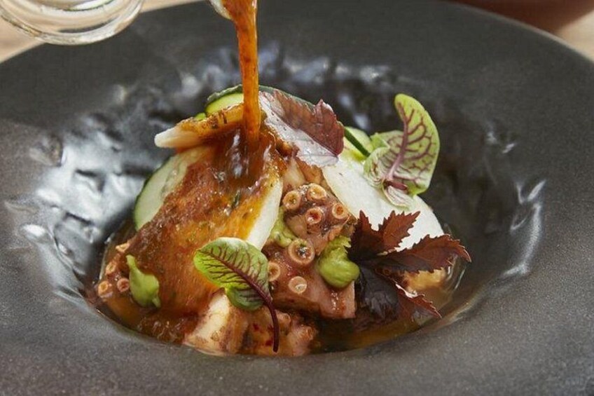 En ret med blæksprutte, grøntsager og sauce på en tallerken. 2