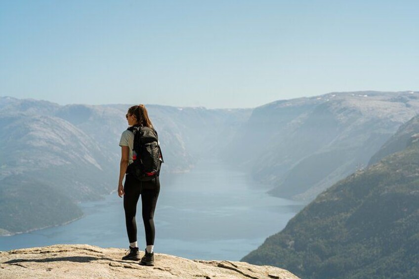 En person står på en klippe med udsigt over en dal med en sø. 1