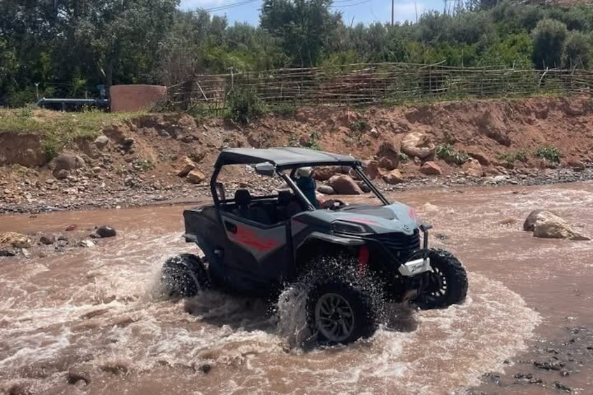 Een voertuig rijdt door een modderige beek. 4