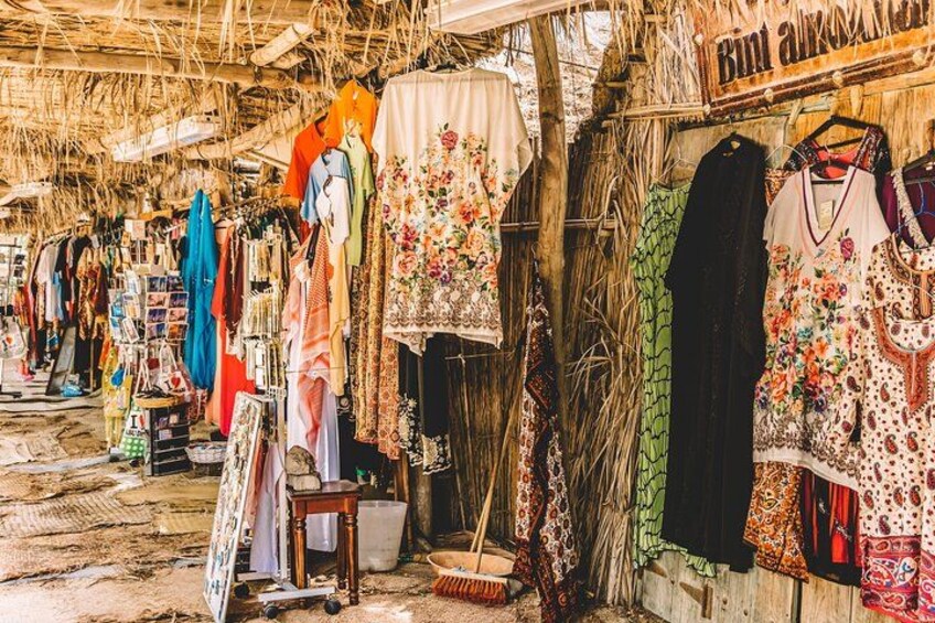 A market stall with various colorful fabrics and clothing items displayed. 2