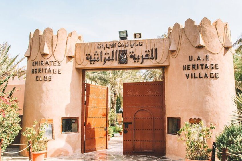 A traditional gate with Arabic script and the name 'U.A.E Heritage Village' on the right. 4