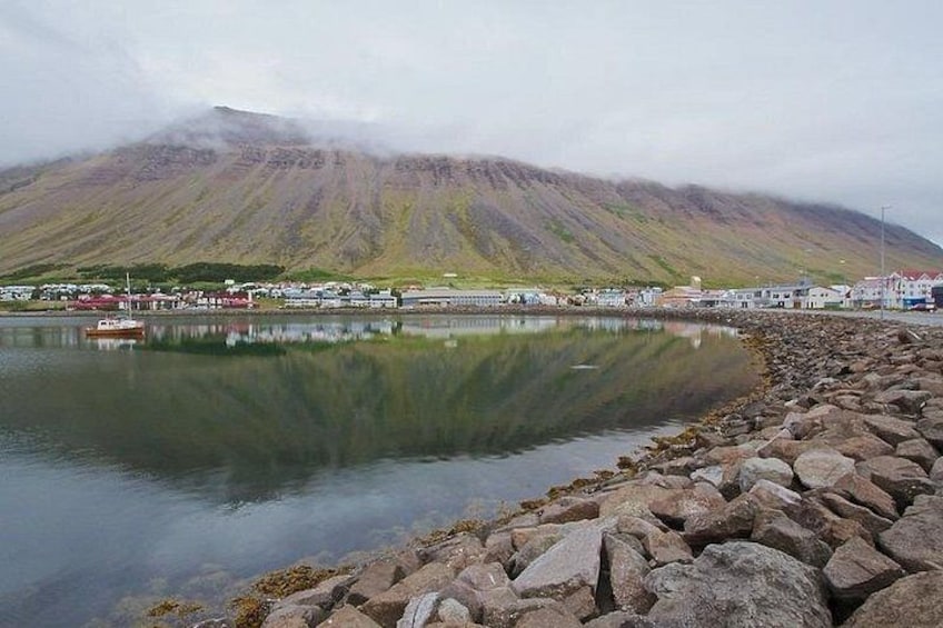 A coastal scene with a rocky shoreline, calm water, and a mountain in the background. 2