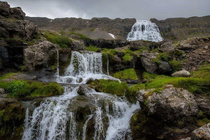 A waterfall cascading over rocks with moss, surrounded by a rocky landscape. 5