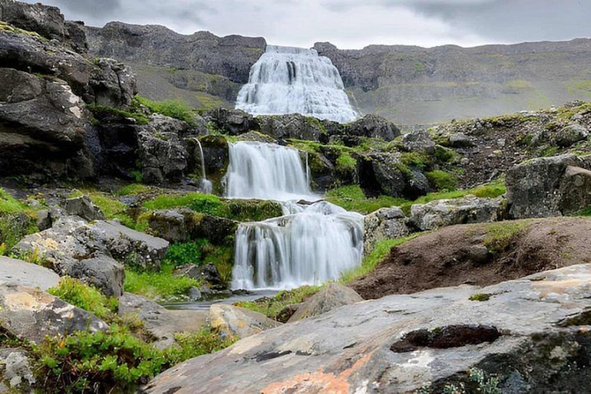 A waterfall cascading over rocks in a mountainous area. 1