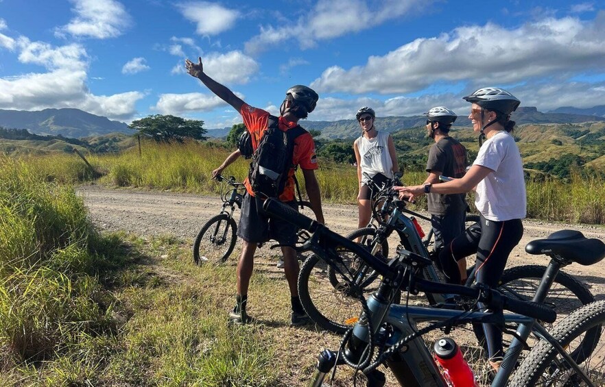 A group of cyclists on a dirt path with mountains in the background. 4