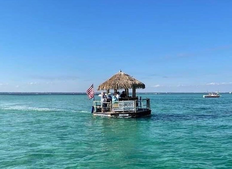 Een boot met een rieten dak en een Amerikaanse vlag, dobberend op kalm turkoois water. 1