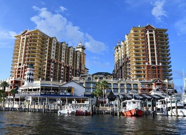 Een waterkant met twee hoge hotels, een steiger met boten, en een klein gebouw met een bord. 4