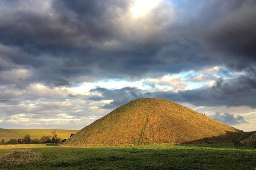 A large mound in a grassy field under a cloudy sky. 3