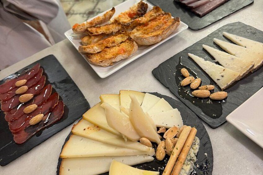 A cheese platter with various cheeses, almonds, and bread. 4