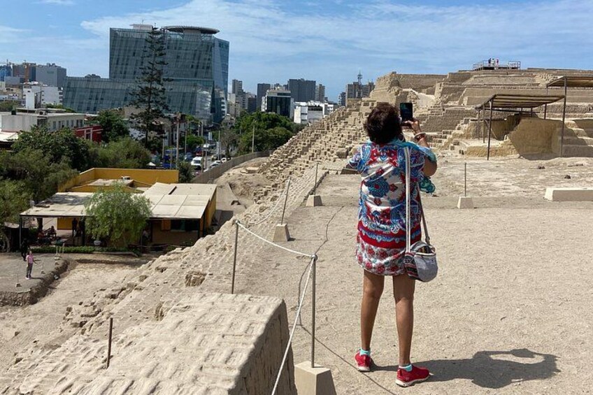 A person taking a photo at an archaeological site with a cityscape in the background. 3