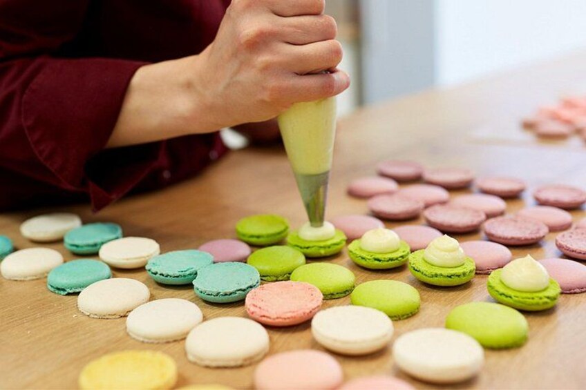 A person decorating macarons with a piping bag. 2