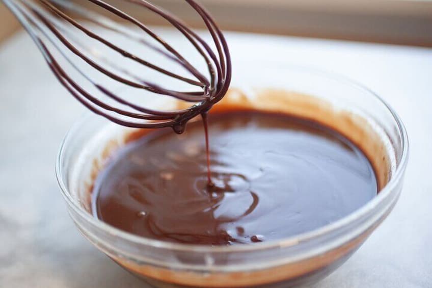 Een garde roert chocolade in een glazen kom. 4