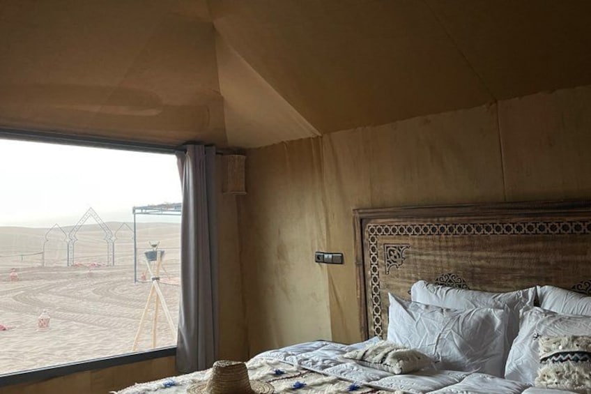 A bedroom with a large bed, a window with a view of a construction site, and a wooden headboard. 4