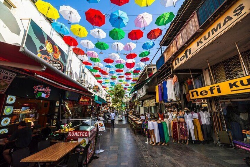Un marché de rue avec des parasols colorés au-dessus et divers commerces. 1