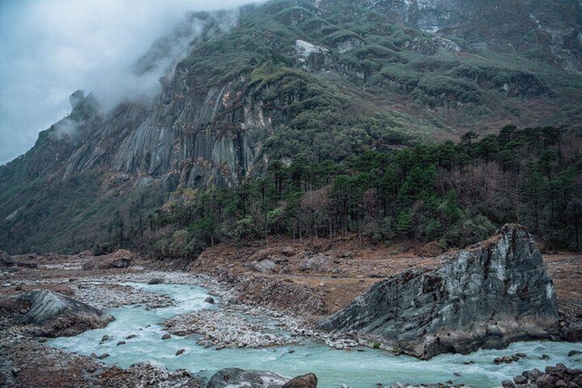 A river flowing through a rocky landscape with steep cliffs and dense forest. 3