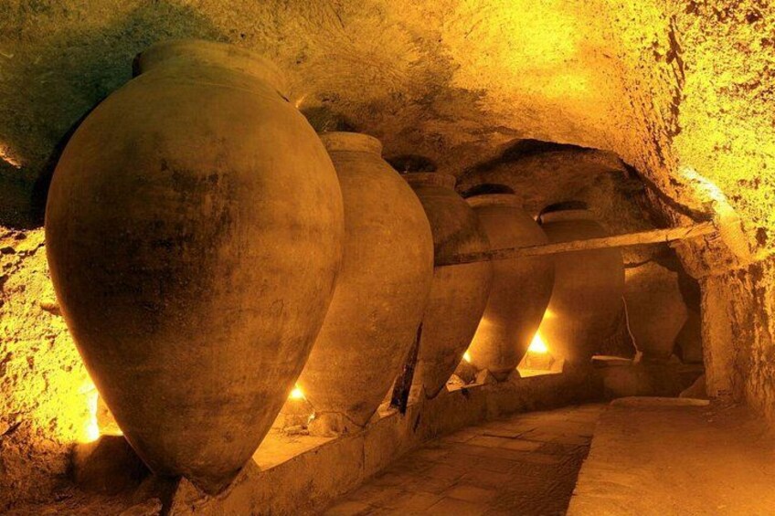 A cave with large stone pots and a narrow passageway. 5