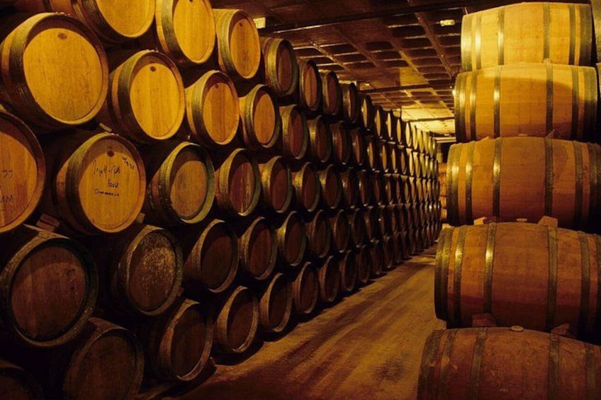 A warehouse filled with wooden barrels stacked in rows. 1