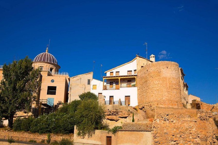 A coastal town with a prominent tower, a church with a dome, and traditional buildings. 3