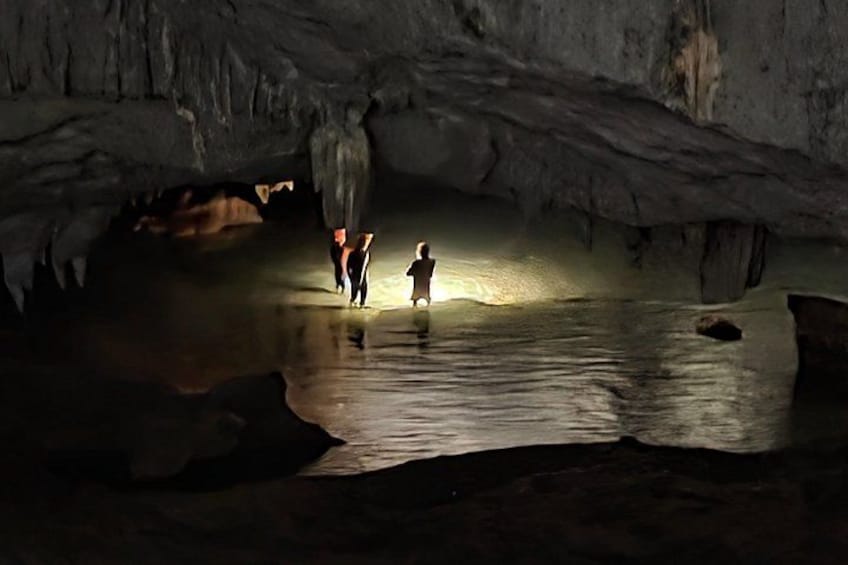 En hule med stalaktitter og stalagmitter, et vandbassin og folk, der udforsker området. 5