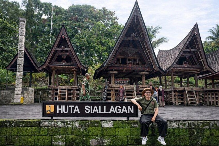 A traditional wooden structure with a sign reading 'Huta Siallagan.' 2