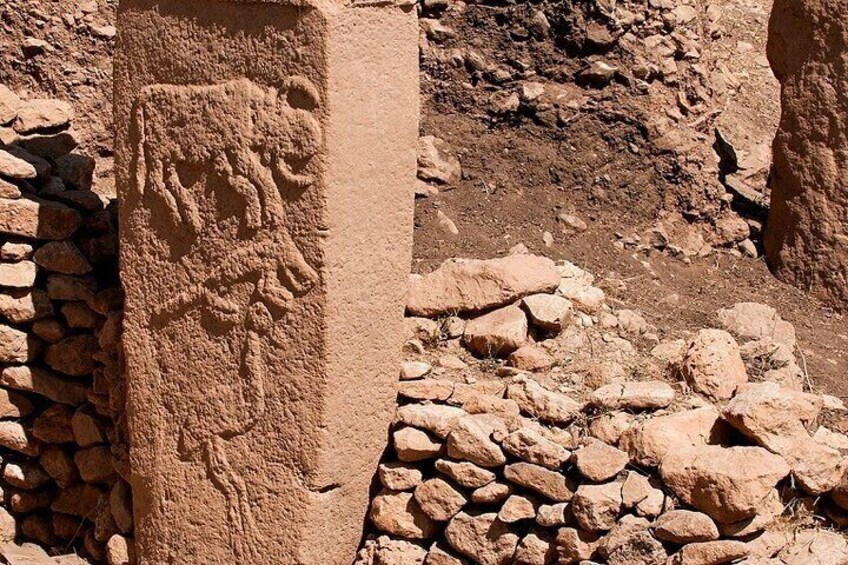 A stone pillar with ancient carvings, surrounded by a rocky terrain. 2