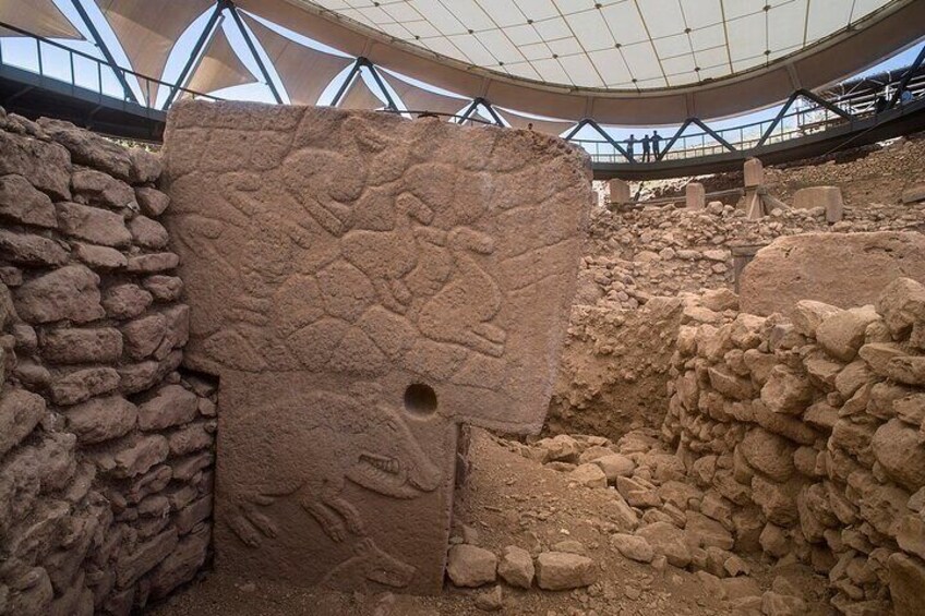 An archaeological site with stone walls and a large carved stone. 3